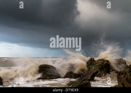 Onde si infrangono intorno rocce durante una tempesta Foto Stock