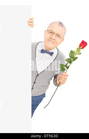 Senior gentleman in piedi dietro il pannello vuoto e mantenendo una rosa rossa Foto Stock