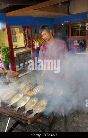 Uomo giavanese Grigliare il pesce in un ristorante, Biak città, isola di Biak, Papua occidentale, in Indonesia Foto Stock