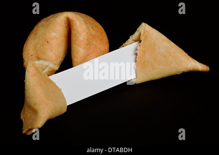 Il cinese fortune cookie su uno sfondo nero su bianco con una striscia di carta per la vostra buona fortuna profezia Foto Stock