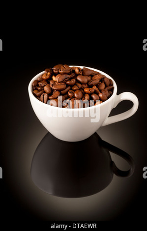 Dark Roast espresso i chicchi di caffè in tazzina di espresso su sfondo riflettente Foto Stock