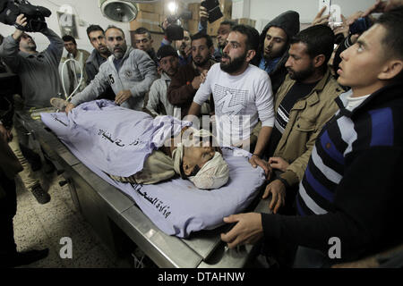 La striscia di Gaza. Xiii Febbraio, 2014. I palestinesi si raccolgono intorno al corpo di Ibrahim Mansour in un ospedale di Gaza City il 13 febbraio, 2014. Un uomo palestinese è stato ucciso giovedì in proiettili israeliani vicino la recinzione di confine tra Hamas-statuito nella Striscia di Gaza e Israele, locale i medici hanno detto. Soldati israeliani hanno aperto il fuoco a un gruppo di lavoratori che sono stati la raccolta di ghiaia vicino al recinto, uccidendo e ferendo un altro, le fonti. Credito: Wissam Nassar/Xinhua/Alamy Live News Foto Stock