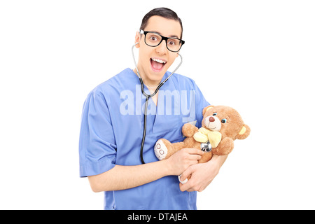 Giovane maschio medico facendo visita medica di controllo su un orsacchiotto Foto Stock