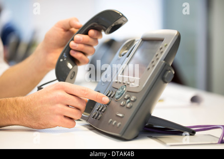 Close-up di mani imprenditore prendere il telefono cellulare del gancio in ufficio Foto Stock
