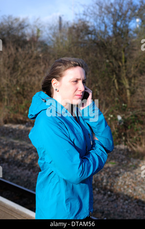 Giovani donne telefono sulla stazione ferroviaria piattaforma . Foto Stock