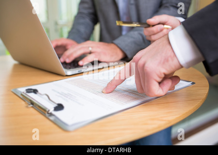 Primo piano delle mani di due imprenditori che lavorano insieme in un ufficio moderno con il computer portatile Foto Stock