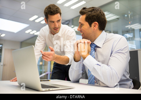 Due imprenditori bello lavorare insieme su un computer portatile in ufficio Foto Stock