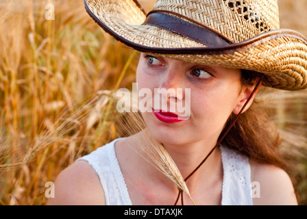 Ragazza nel campo di grano in abito bianco e stetson hat. Messa a fuoco selettiva. Foto Stock