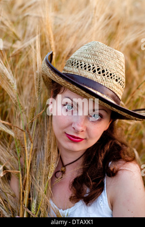 Ragazza nel campo di grano in abito bianco e stetson hat. Messa a fuoco selettiva. Foto Stock