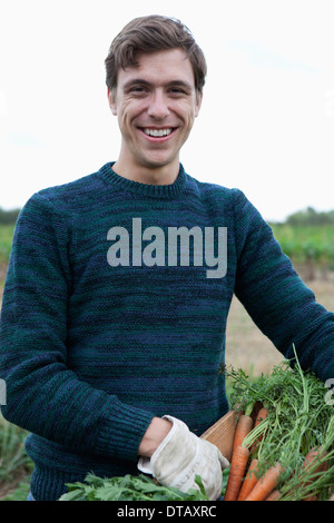 Uomo con carote raccolte nel campo, ritratto Foto Stock