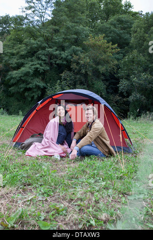 Coppia giovane seduto vicino a tenda a cupola, sorridente Foto Stock