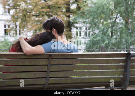 Coppia giovane seduto su una panchina nel parco, vista posteriore Foto Stock