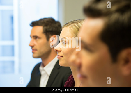 Tre colleghi seduti ad una riunione di affari, concentrarsi sulla bella donna Foto Stock