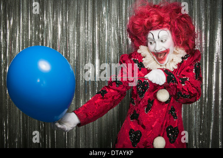 Un clown prepararsi al pop di un palloncino con un ago Foto Stock