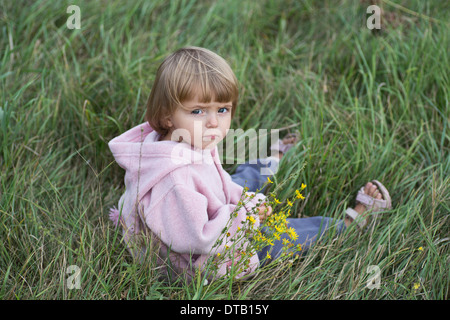 Ragazza seduta su erba, ritratto Foto Stock