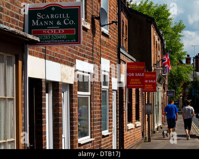 In vendita e venduto i segni al di fuori del tradizionale rosso mattone case a schiera in Tutbury Inghilterra Staffordshire REGNO UNITO Foto Stock