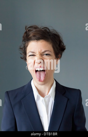 Metà donna adulta con la lingua fuori nel disgusto, close-up Foto Stock
