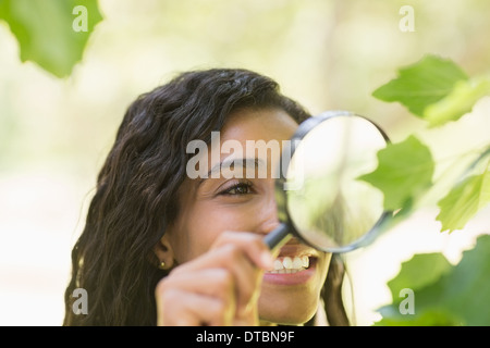 Donna esaminando foglie con lente di ingrandimento Foto Stock