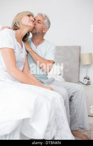 Uomo maturo kissing womans guancia a letto Foto Stock
