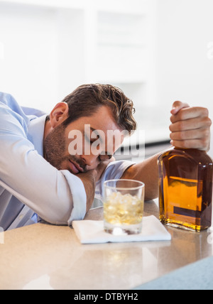 Imprenditore ubriaco che impugnano whiskey bottiglia addormentato Foto Stock