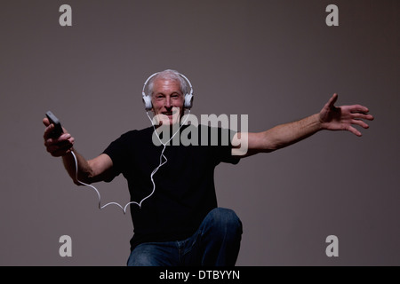 Ritratto di uomo anziano ballando al lettore MP3 sulle cuffie Foto Stock