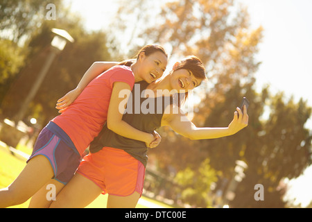 Due giovani donne che assumono ritratto di auto in parcheggio Foto Stock