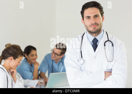 Medico maschio in piedi con le braccia incrociate Foto Stock