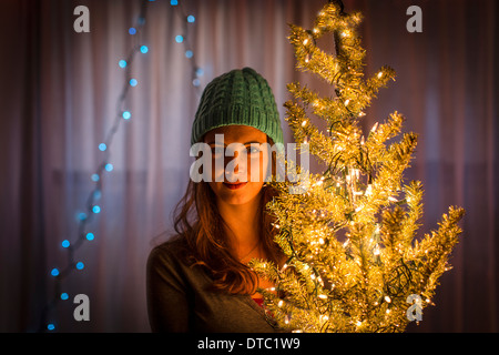 Ritratto di giovane donna azienda albero di natale Foto Stock