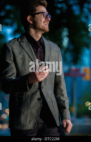 Giovane uomo passeggiando per strada con il telefono cellulare, Toronto, Ontario, Canada Foto Stock