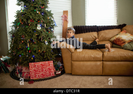 Maschio eccitato toddler guardando le decorazioni su albero di natale Foto Stock