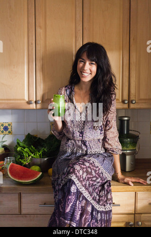 Giovane donna in cucina con succo di verdura Foto Stock