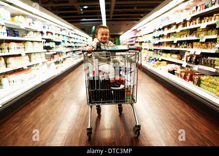 Bambino seduto nel carrello per supermercati Foto Stock