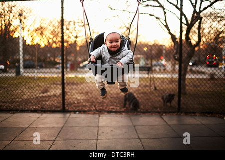 Bambino seduto su swing in posizione di parcheggio Foto Stock