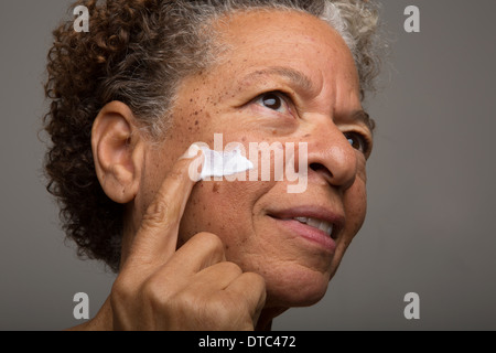 Close up studio ritratto di donna senior l'applicazione di crema per il viso Foto Stock