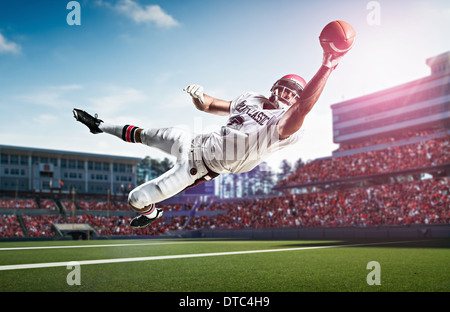 Giocatore di football americano la cattura di sfera metà aria nel Stadium Foto Stock