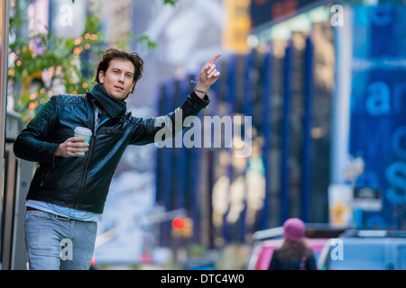 Giovane maschio tourist salutando una cabina, New York City, Stati Uniti d'America Foto Stock