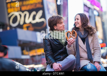 Coppia giovane la condivisione pretzel, New York City, Stati Uniti d'America Foto Stock