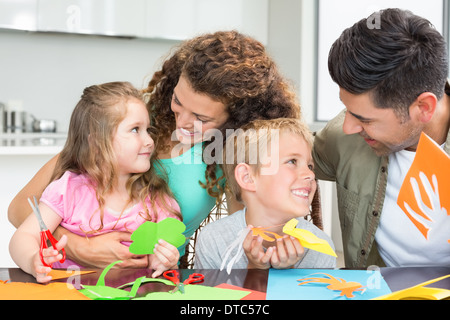 Sorridente giovane famiglia facendo arti e mestieri a tavola Foto Stock