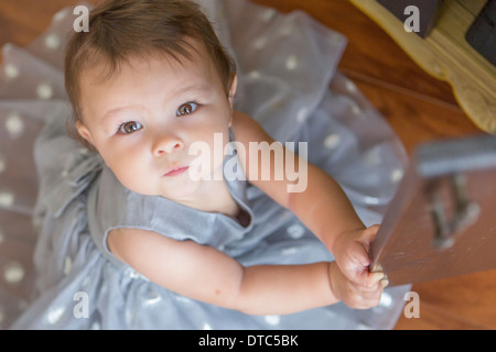 Bambina indossa party dress, guardando verso l'alto Foto Stock