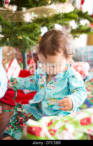 Baby girl aprendo i regali di Natale sul suo primo Natale Foto Stock