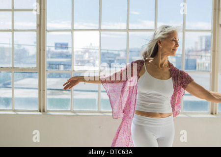 Grazioso senior woman dancing in appartamento soleggiato Foto Stock