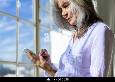 Senior donna utilizzando il touchscreen sullo smartphone Foto Stock