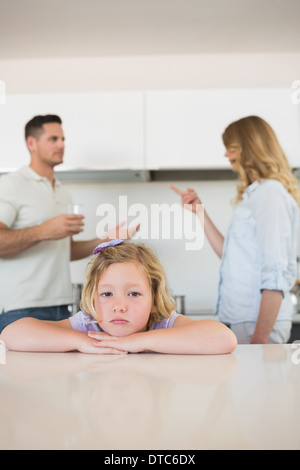 Ragazza triste appoggiata sul tavolo mentre i genitori in conflitto Foto Stock