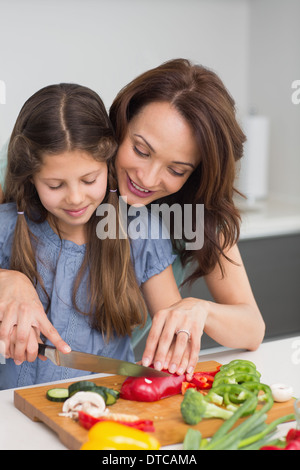 Donna con figlia tritare verdure in cucina Foto Stock