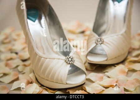 Elegante raso bianco scarpe con i tacchi alti con sparky effetto diamantato decorazione per una sposa, artificiale con petali di rosa Foto Stock