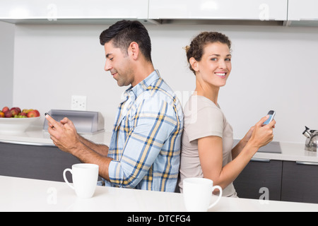 Sorridente giovane seduto di schiena texting Foto Stock