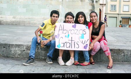 Oaxaca, Messico; Febbraio 14, 2014: quattro sorridente adolescenti messicani azienda artigianale di segno offrendo free hugs per il giorno di San Valentino Credito: Dorothy Alexander/Alamy Live News Foto Stock