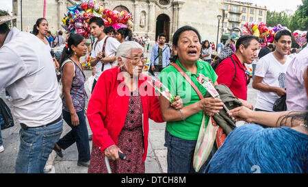 Oaxaca, Messico; Febbraio 14, 2014: vecchia signora messicana e sua figlia, fra la folla di fronte la Cattedrale di Oaxaca, sono molto lieto di ricevere cellophane avvolto i cuori a nome di un candidato per la carica politica Credito: Dorothy Alexander/Alamy Live News Foto Stock