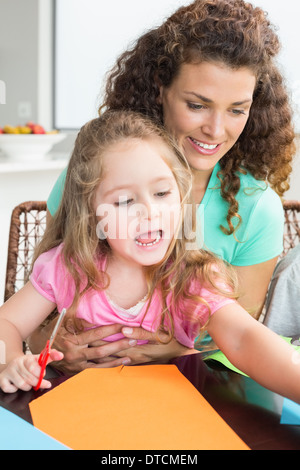 Allegro bambina facendo arti e mestieri con la madre a tavola Foto Stock