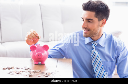 Imprenditore bello mettere monete nel salvadanaio Foto Stock